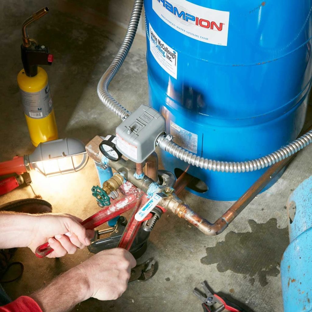 Technicien vérifiant le condensateur et les connexions d'une pompe à eau en panne à Douala
